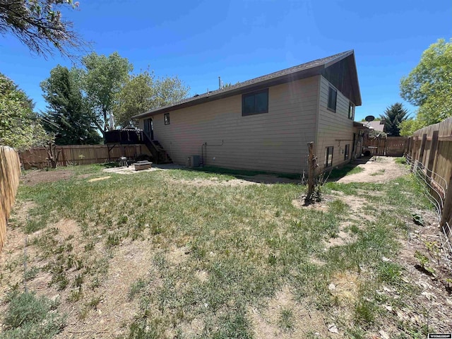 view of side of home with cooling unit and a yard