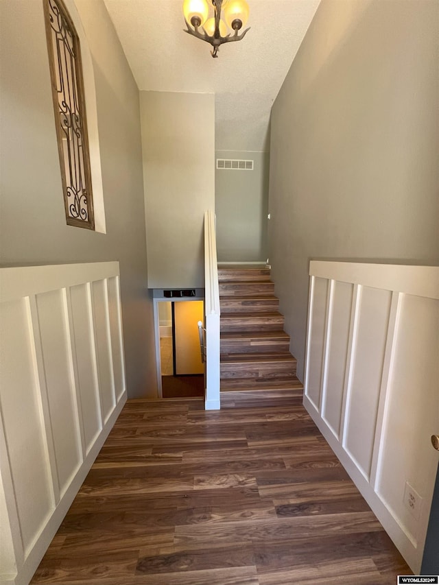 staircase featuring a chandelier, a textured ceiling, hardwood / wood-style flooring, and lofted ceiling