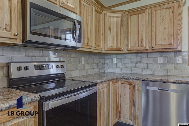 kitchen featuring tasteful backsplash, appliances with stainless steel finishes, and dark stone countertops