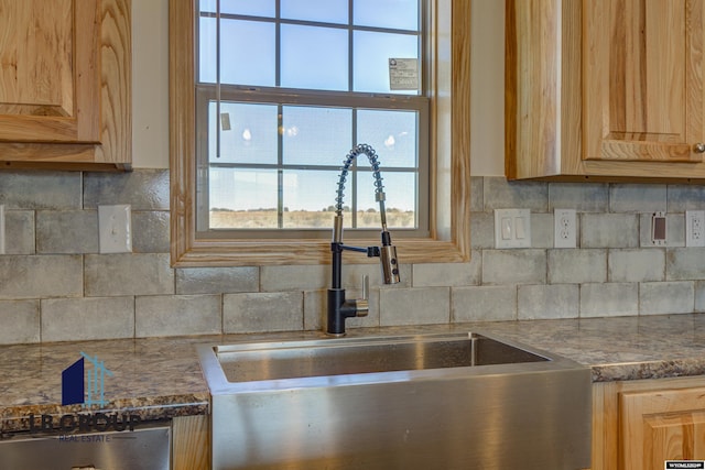 kitchen with light brown cabinetry, sink, and backsplash