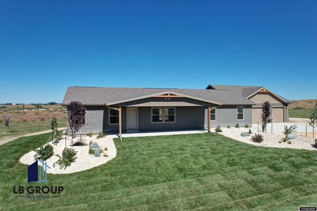 view of front of home featuring a rural view, a garage, and a front lawn