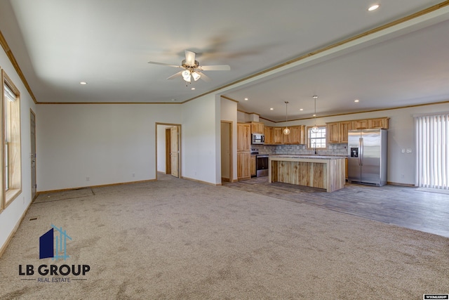 kitchen with crown molding, a center island, light carpet, appliances with stainless steel finishes, and pendant lighting