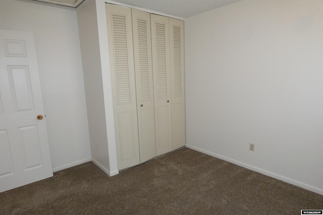 unfurnished bedroom with a closet and dark colored carpet