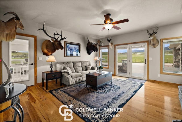 living room featuring a textured ceiling, light hardwood / wood-style flooring, and ceiling fan