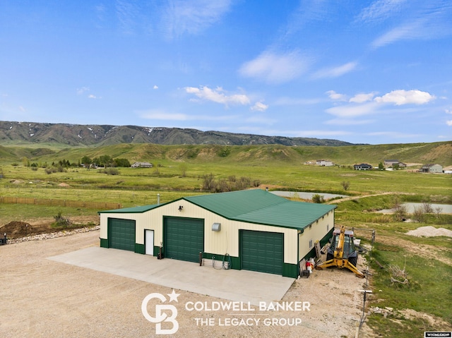 view of outdoor structure featuring a garage, a mountain view, and a rural view