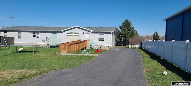 exterior space with a trampoline, fence, and a front lawn