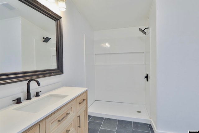 bathroom with a shower, vanity, and tile patterned floors