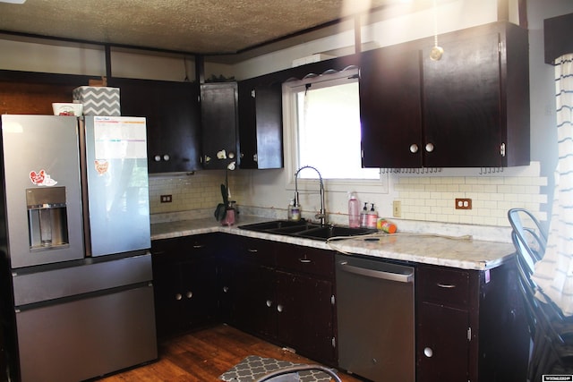 kitchen with tasteful backsplash, dark wood-type flooring, a textured ceiling, sink, and appliances with stainless steel finishes