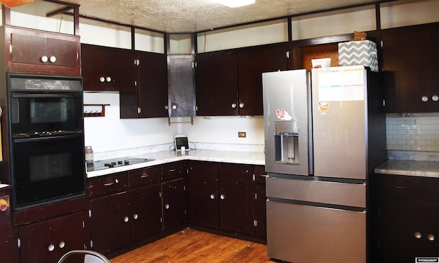 kitchen with black appliances, hardwood / wood-style flooring, dark brown cabinetry, and a textured ceiling