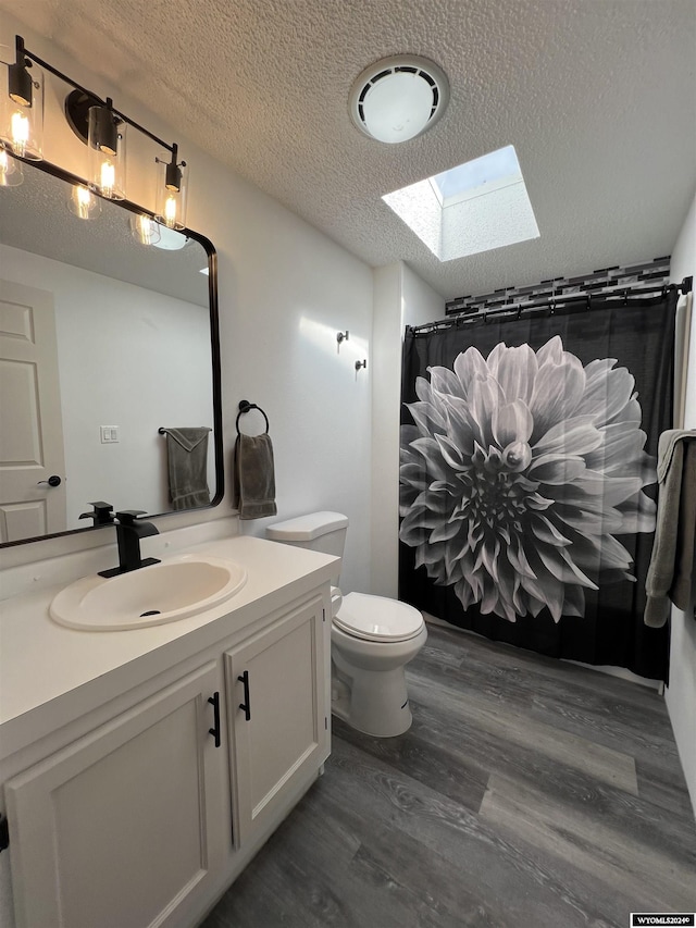 bathroom with a skylight, vanity, wood-type flooring, and a textured ceiling