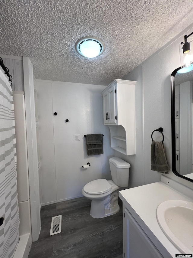 bathroom with hardwood / wood-style floors, vanity, toilet, a textured ceiling, and walk in shower