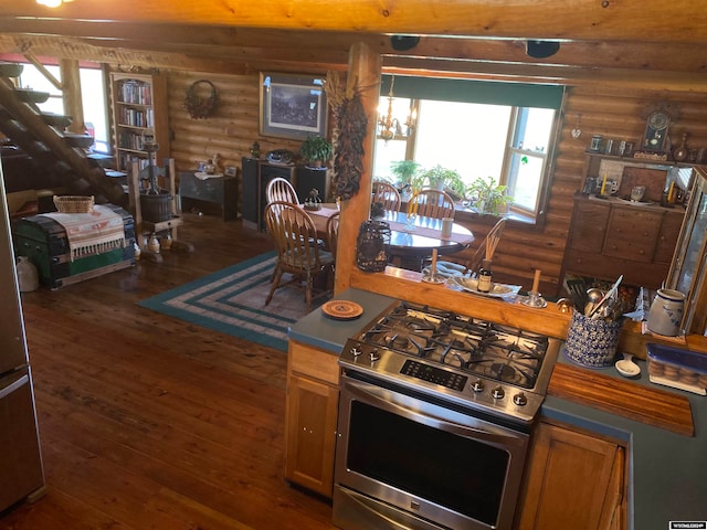 kitchen featuring a notable chandelier, stainless steel gas range oven, rustic walls, and wood-type flooring