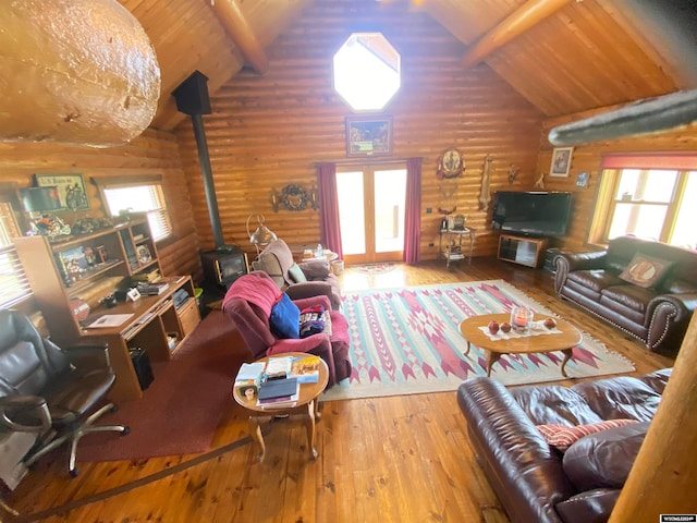 living room featuring beamed ceiling, a wealth of natural light, and a wood stove