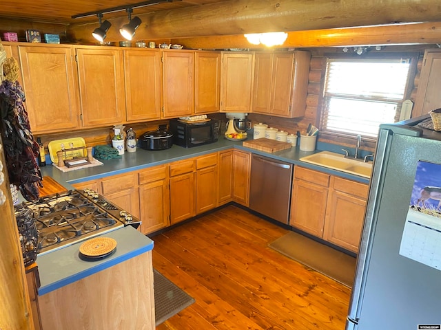 kitchen with stainless steel appliances, beam ceiling, sink, and hardwood / wood-style flooring