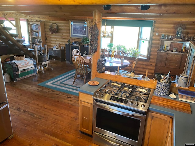 kitchen featuring a notable chandelier, log walls, hardwood / wood-style flooring, and stainless steel range with gas stovetop