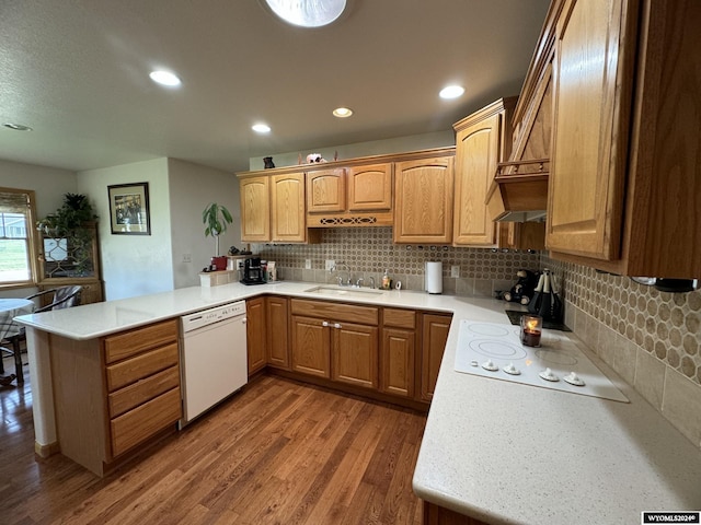 kitchen with sink, tasteful backsplash, kitchen peninsula, wood-type flooring, and white appliances