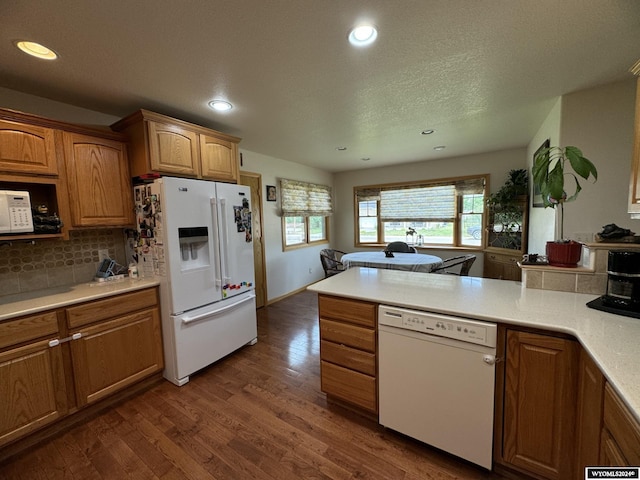 kitchen featuring a textured ceiling, white appliances, dark hardwood / wood-style floors, and backsplash