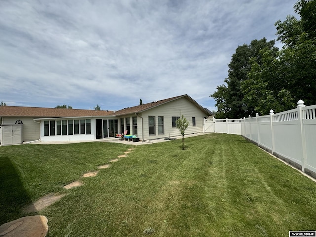 back of house featuring a lawn, a sunroom, and a patio area