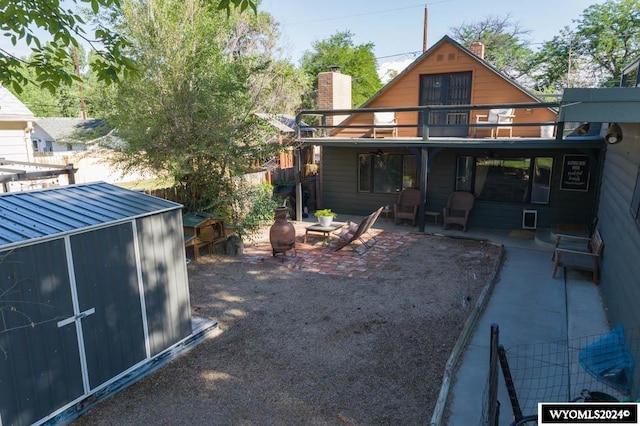 rear view of property with a patio, a balcony, and a shed