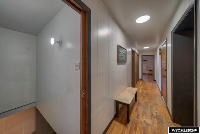 hallway with light hardwood / wood-style flooring and wood walls