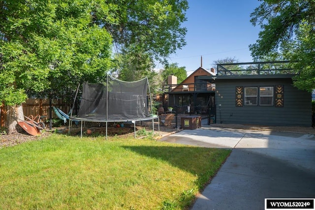 view of yard with a trampoline and a patio