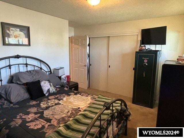 carpeted bedroom featuring a textured ceiling and a closet