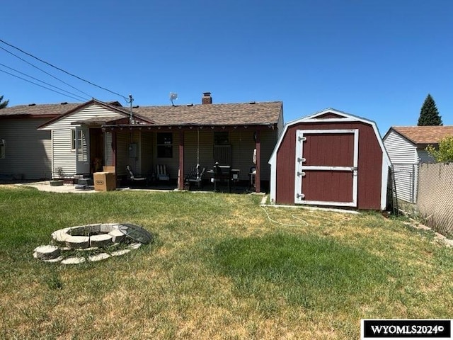 rear view of property featuring a yard, a fire pit, and a storage unit