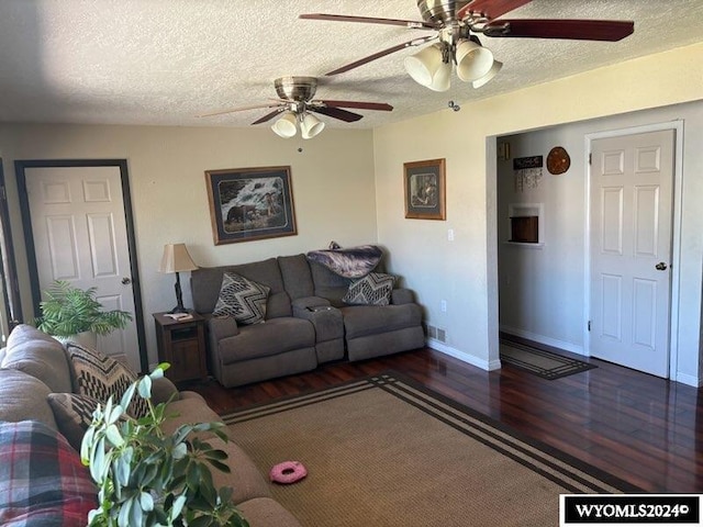 living room featuring a textured ceiling, ceiling fan, and dark wood-type flooring