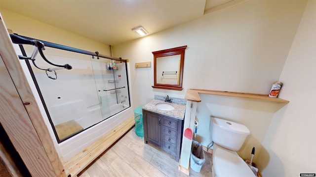 full bathroom featuring combined bath / shower with glass door, toilet, and vanity