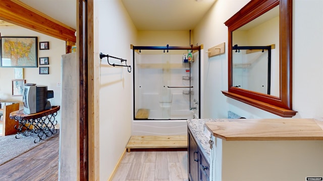 bathroom with bath / shower combo with glass door, hardwood / wood-style floors, and vanity