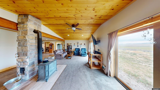 interior space with a wood stove, wooden ceiling, ceiling fan, and plenty of natural light