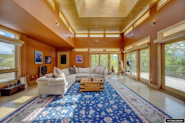 living room featuring wood ceiling, light hardwood / wood-style floors, and a high ceiling