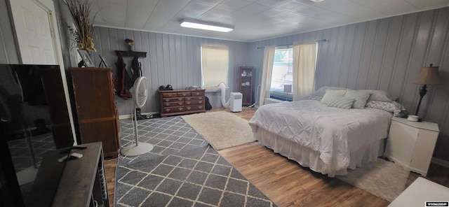 bedroom with wooden walls and hardwood / wood-style floors