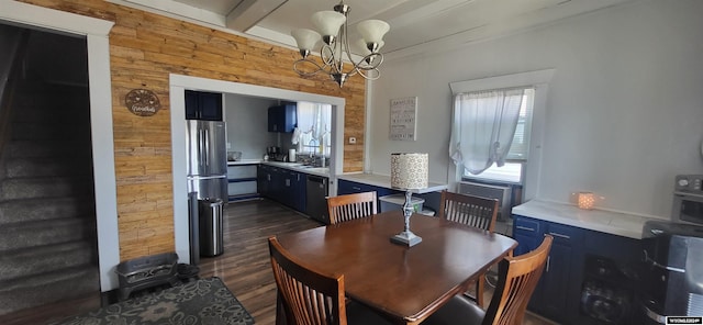 dining space featuring sink, an inviting chandelier, beamed ceiling, dark hardwood / wood-style floors, and wooden walls