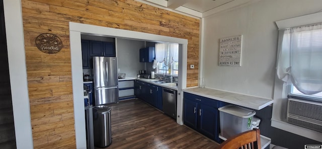 kitchen with appliances with stainless steel finishes, blue cabinetry, wooden walls, and dark wood-type flooring