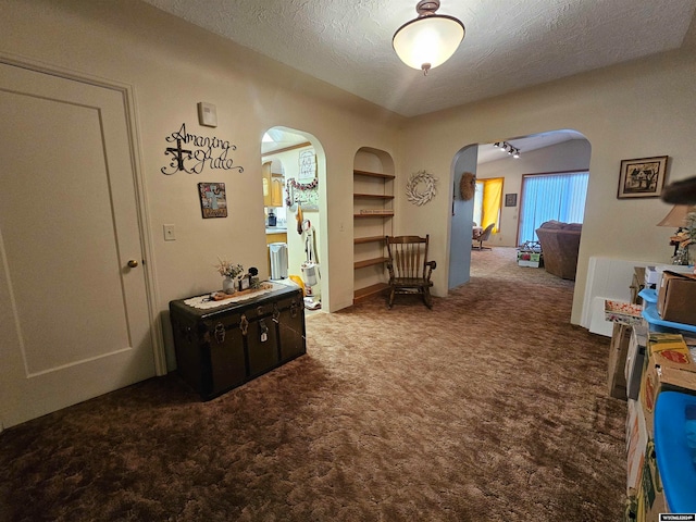 hallway featuring carpet flooring and a textured ceiling