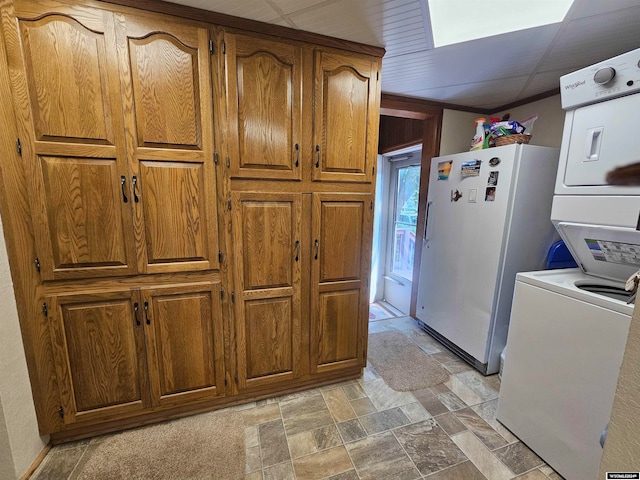 kitchen featuring white refrigerator, a paneled ceiling, light tile patterned floors, and stacked washing maching and dryer