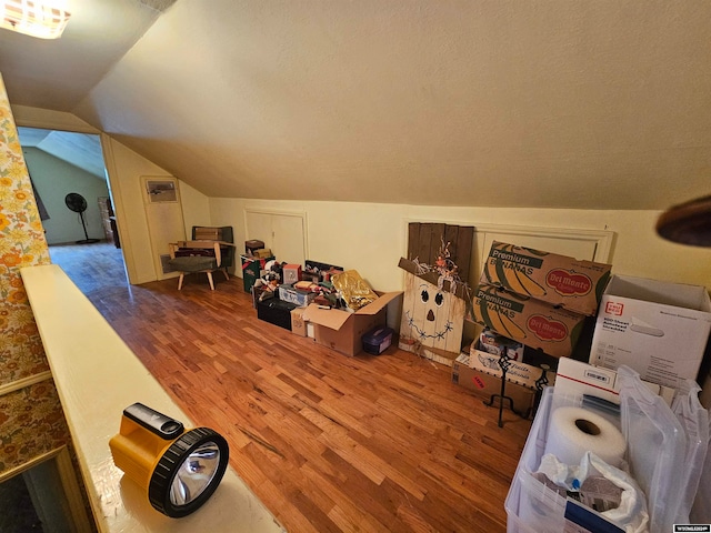 additional living space with lofted ceiling, wood-type flooring, and a textured ceiling