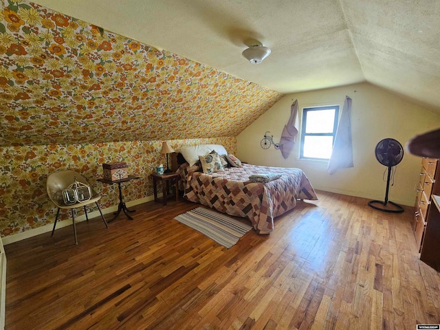 bedroom featuring vaulted ceiling, hardwood / wood-style floors, and a textured ceiling