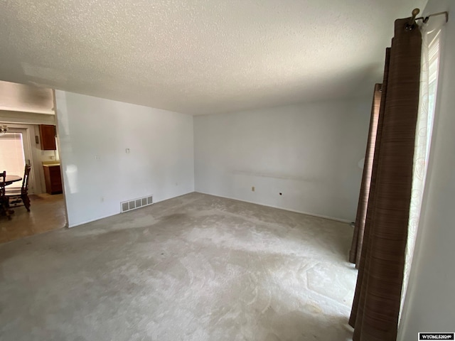 spare room featuring a textured ceiling and carpet floors