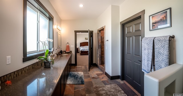 bathroom featuring a wealth of natural light, baseboards, ensuite bath, and stone finish floor