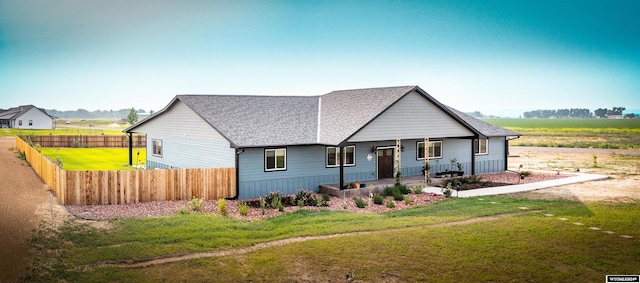 view of front of property featuring a front yard, fence, covered porch, and roof with shingles