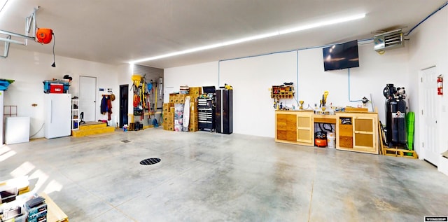 garage featuring water heater, a workshop area, and freestanding refrigerator