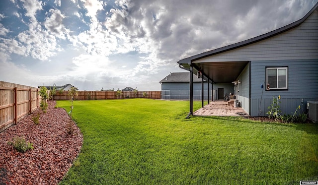 view of yard featuring central AC unit, a fenced backyard, and a patio area