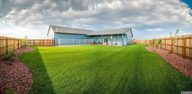 rear view of property with a yard and a fenced backyard