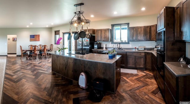 kitchen featuring black appliances, dark stone countertops, a kitchen island, recessed lighting, and dark brown cabinetry