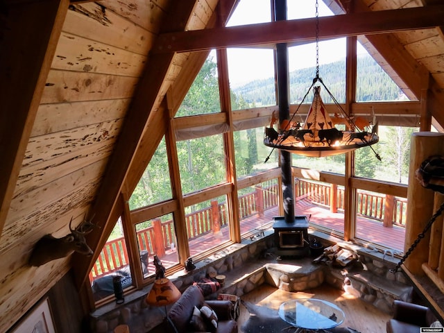 unfurnished living room with a wood stove, an inviting chandelier, beamed ceiling, wooden ceiling, and high vaulted ceiling