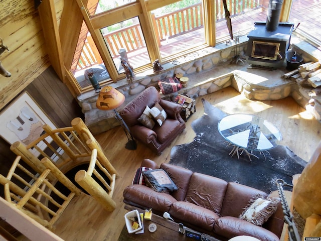 living room with a wood stove, hardwood / wood-style floors, and a towering ceiling