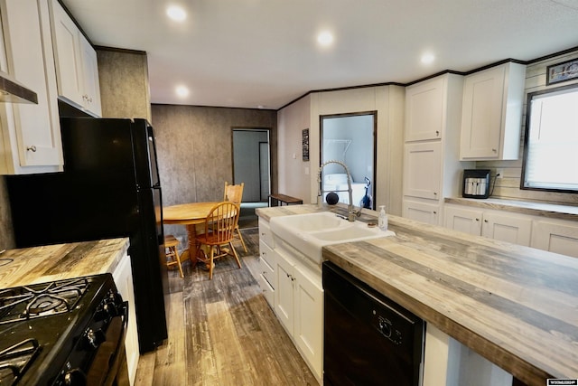 kitchen featuring butcher block counters, sink, white cabinetry, and black appliances