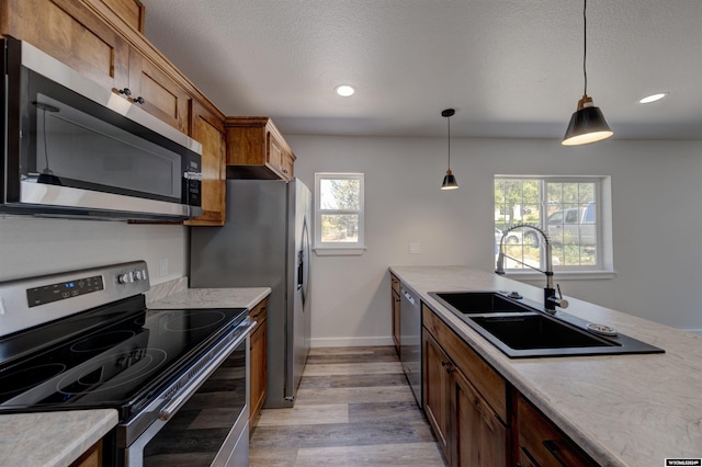 744 E Loucks St, Sheridan, WY 82801 - kitchen featuring a textured ceiling, sink, decorative light fixtures, light hardwood / wood-style flooring, and stainless steel appliances